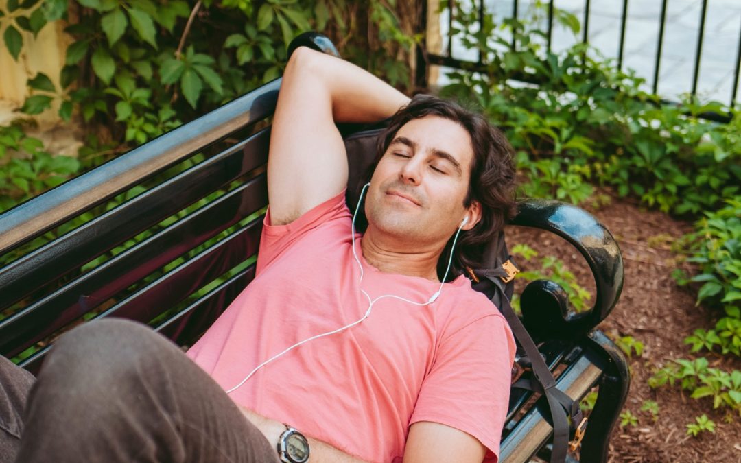 relaxed man listening to audio meditations park bench